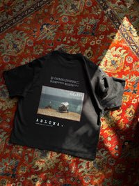 Black t-shirt with a graphic design on a red patterned rug